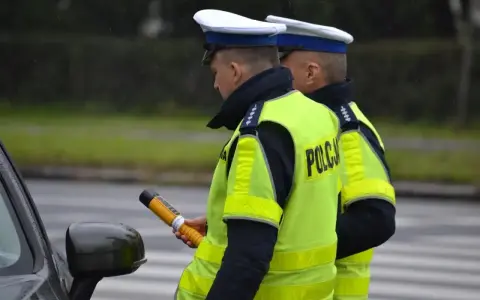 Policjant w kamizelce odblaskowej trzyma alkomat. Czy policja może badać alkomatem w domu? To pytanie często zadawane przez kierowców.