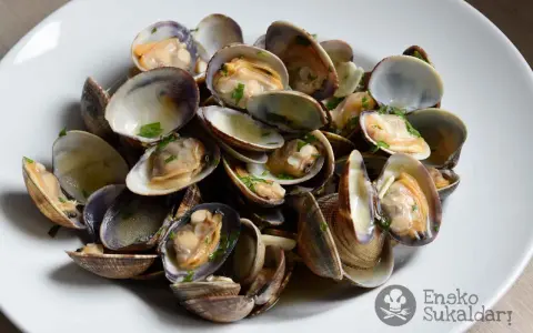 Un plato de almejas a la marinera, jugosas y recién cocinadas, con perejil picado.