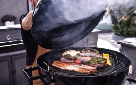 Fumo sale da una grigliata di carne succulenta, con salsicce, hamburger e pancetta che sfrigolano.