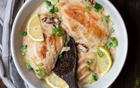 Deliziose scaloppine al vino bianco in una cremosa salsa, guarnite con limone, broccoli e piselli. Un piatto invitante e saporito.