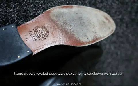 Widok od spodu buta z wytłoczonym logo "CLUE SHOES" i napisem "POLISH HANDCRAFTED". Twarda podeszwa skórzana nosi ślady użytkowania.