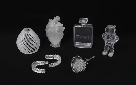 A collection of 3D printed acrylic objects: a vase, heart, dental aligners, perfume bottle, rose, and astronaut.