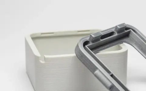 Close-up of a 3D-printed white box and a grey lid, showcasing the intricate snap fit joints designed for easy assembly.