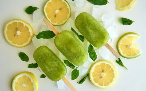 Trois bâtonnets glacés verts, comme une coupe colonel rafraîchissante, entourés de citrons, de menthe et de glaçons.