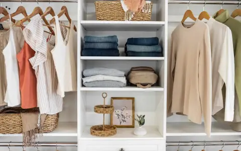 A well-organized closet with hanging clothes, folded jeans, sweaters, and decorative baskets. This DIY closet organizer maximizes space and style.