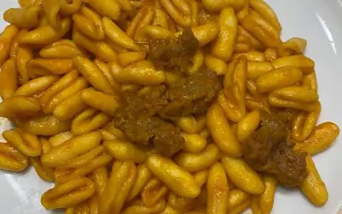 Un piatto invitante di gnocchetti alla campidanese, conditi con un sugo ricco e pezzetti di carne saporita.