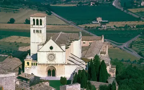 Basilica of Saint Francis of Assisi, a stunning example of Italian monasteries, with its iconic bell tower and rose window, nestled in a verdant landscape.