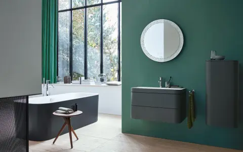 Un baño moderno con bañera oscura, lavabo flotante y espejo decorativo. La pared verde es un lienzo perfecto para pintar el baño.