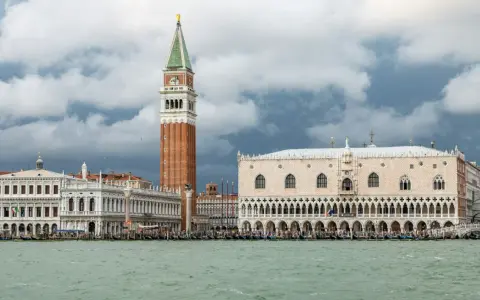 Weneckie budowle, w tym Pałac Dożów i Kampanila, na tle burzowych chmur. Venezia to miasto, które zachwyca.