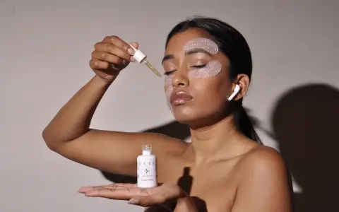 Donna applica siero con contagocce, ha maschera occhi e auricolari. Chissà ogni quanto maschera occhi per un viso radioso.