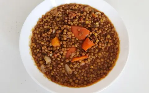 Un plato de lentejas guisadas con zanahoria y cebolla, cocinadas en olla express. Un plato reconfortante y rápido.