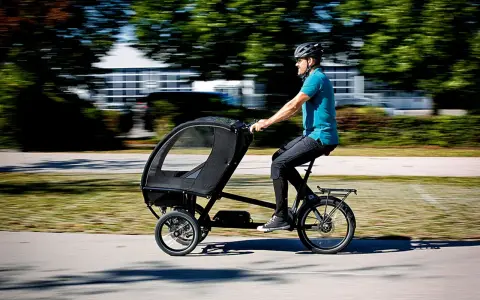 Mann fährt ein Lastenrad mit Kabine, ideal für lastenrad erwachsene transportieren.