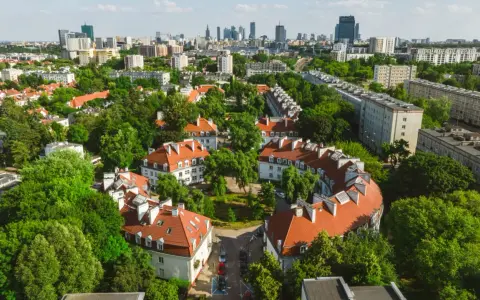 Zielony Żoliborz Oficerski z charakterystyczną architekturą i panoramą miasta w tle.