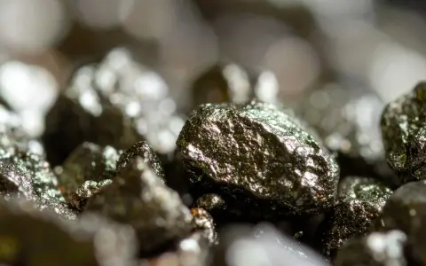Zbliżenie na błyszczące bryłki pirytu, ukazujące jego metaliczny połysk i nierówną powierzchnię. Piryt właściwości tego minerału fascynują.