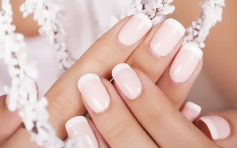 Mani curate con unghie french impeccabili, incorniciate da delicati fiori bianchi.