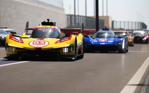 Gelber Ferrari Le Mans Hypercar mit Startnummer 83 und blauer Konkurrenz auf der Rennstrecke.