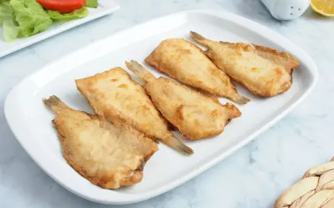 Cinco acedias fritas doradas y crujientes en una bandeja blanca, listas para disfrutar.