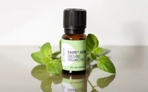 Szukasz, gdzie kupić olejek z oregano? Na zdjęciu buteleczka z organicznym olejkiem z oregano, otoczona świeżymi gałązkami.