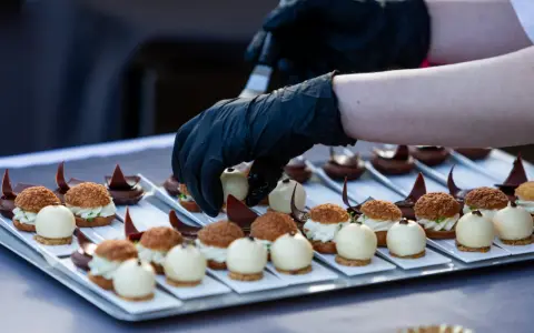 Mains de chef en gants noirs disposant des bouchées, une spécialité culinaire de Metz, sur un plateau.