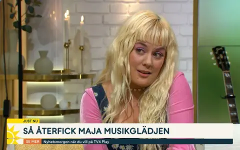 Maja Francis, med sitt blonda hår och rosa tröja, pratar om hur hon återfick sin musikglädje. En gitarr syns i bakgrunden.