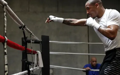 Un boxeur s'entraîne en shadow boxing dans un ring, concentré sur ses mouvements.