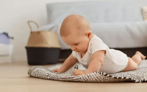 Dziecko na brzuchu, ćwiczy **wysoki podpór kiedy** na dywaniku.