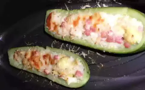 Zucchine ripiene di riso, condite con pomodoro e formaggio, pronte per essere gustate.