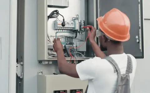 Elektryk w kasku sprawdza instalację fotowoltaiczną. Dowiedz się, jak obniżyć napięcie w sieci fotowoltaika.