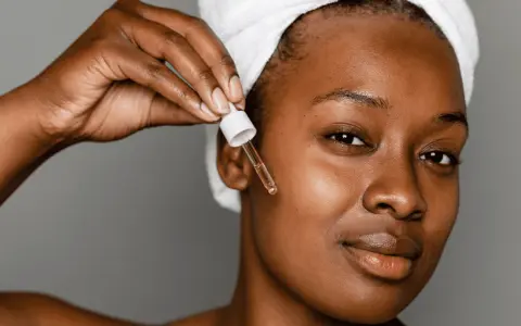 A woman applies a serum with peptides for acne, a step in her skincare routine.
