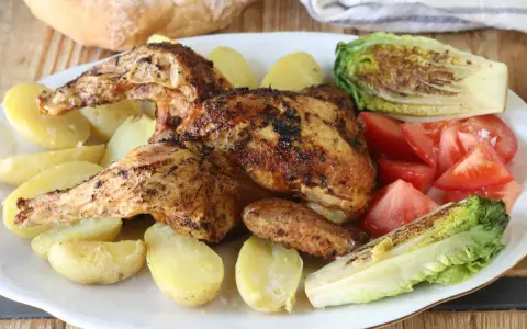 Pollo a la brasa jugoso y dorado, acompañado de papas amarillas, tomates frescos y lechuga a la parrilla. Un festín para los sentidos.