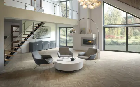 Salon moderne avec un **plafond cathédrale moderne**, escalier flottant, cheminée et grandes baies vitrées donnant sur un jardin.