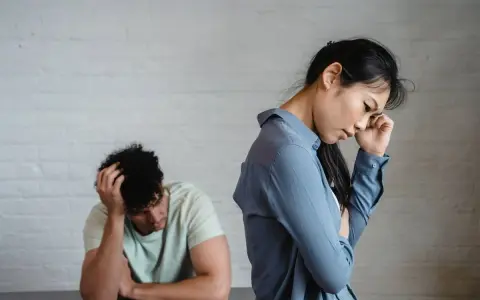 Pareja en silencio, ella con la mano en la frente, él con la cabeza entre las manos. Un ambiente de tensión pasivo agresivo.