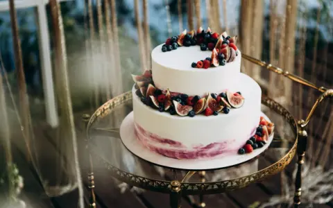 Elegancki tort piętrowy na 40 osób, ozdobiony świeżymi figami, borówkami i malinami. Idealny na wyjątkowe przyjęcie.
