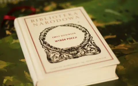 Biała księga z napisem "Emily Dickinson Wybór Poezji" w ozdobnej ramce.