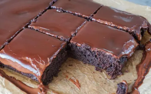 Saftige, vegane Brownies mit glänzendem Schokoladenguss, in Quadrate geschnitten. Ein Genuss für alle Schokoladenfans!