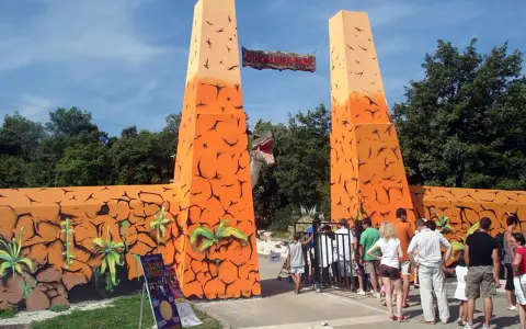 Eingang zum Dinosaurier-Park, einem Freizeitpark in Kroatien. Eine Gruppe von Besuchern steht vor dem Eingangstor.