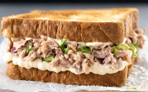 Pyszna kanapka z tuńczykiem, pełna kremowego majonezu i świeżej sałaty, idealna na szybki lunch.