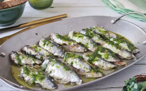 Deliciosas sardinas al horno, cubiertas con una sabrosa salsa verde, listas para disfrutar.
