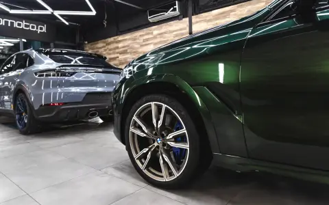 Lśniące, zielone BMW i szare Porsche w garażu. To efekt profesjonalnego auto detailingu, który przywraca blask lakierowi i dba o każdy detal pojazdu.