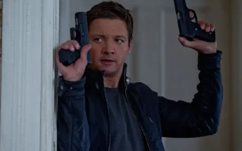 Jeremy Renner som Aaron Cross i rollistan i Jason Bourne-filmerna, redo för action med två pistoler.