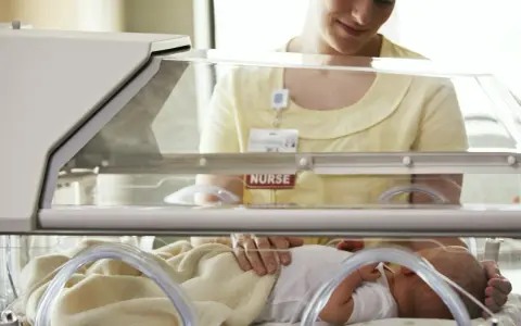 Pielęgniarka opiekuje się dzieckiem urodzonym w 32 tygodniu ciąży w inkubatorze.