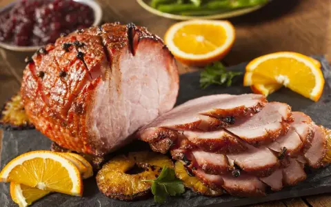 Pieczona szynka z pomarańczą i ananasem, idealna do świątecznego stołu. Marynata do szynki nadała jej piękny kolor i aromat.