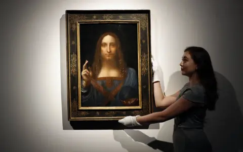En kvinna med vita handskar hanterar den berömda tavlan "Salvator Mundi", ibland kallad "Mona Lisa tavla" av misstag.