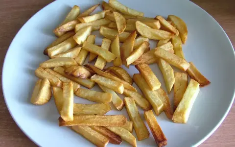 Złociste frytki z piekarnika na talerzu. Zastanawiasz się, ile kcal mają frytki z piekarnika? Oto porcja pysznych, pieczonych ziemniaków.