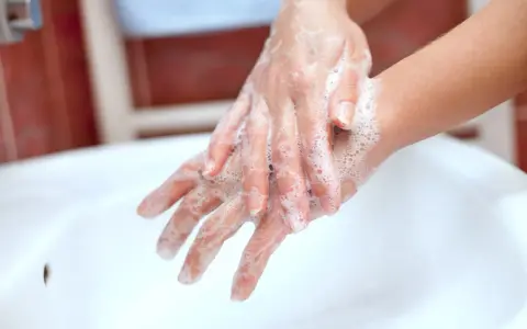 Mani insaponate che dimostrano come è fatto il sapone, creando una schiuma soffice per pulire.