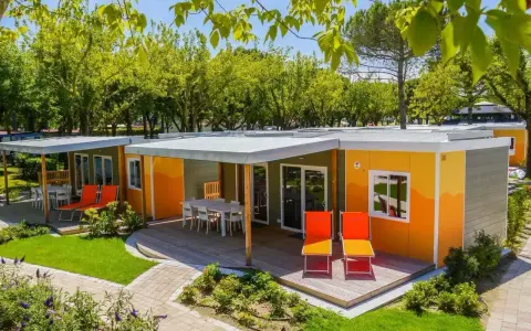 Kolorowe domki na kempingu, z tarasami i leżakami, otoczone zielenią. Prawdziwy camping garden paradiso!