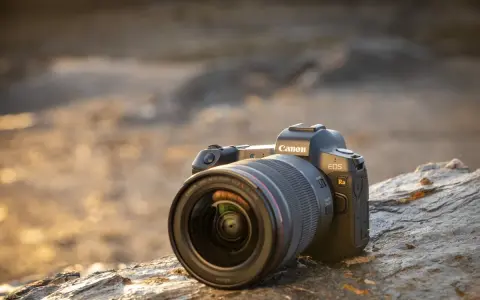 Aparat Canon EOS Ra z obiektywem RF 15-35mm f/2.8L IS USM leży na kamieniu.