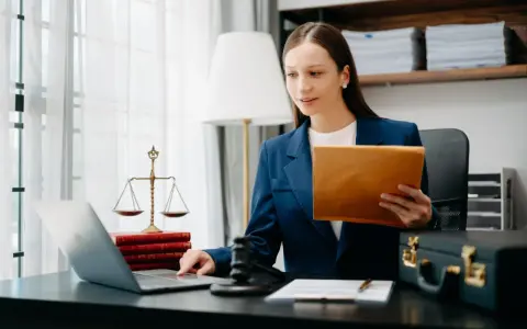 Prawniczka pracuje nad sprawą wdrożenie windykacji, analizując dokumenty na laptopie.
