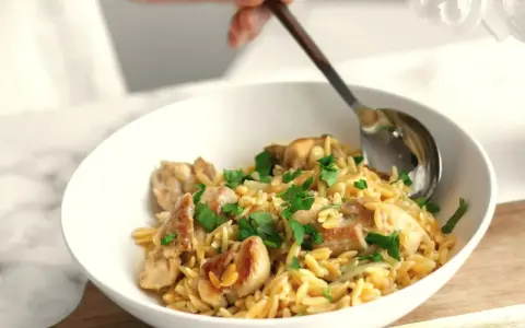 Szybki obiad z makaronem orzo i kurczakiem, posypany natką pietruszki. Idealny na szybki posiłek.