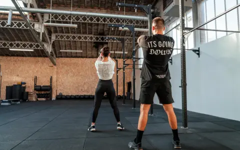 Para ćwicząca z kettlebell w siłowni CrossFit.